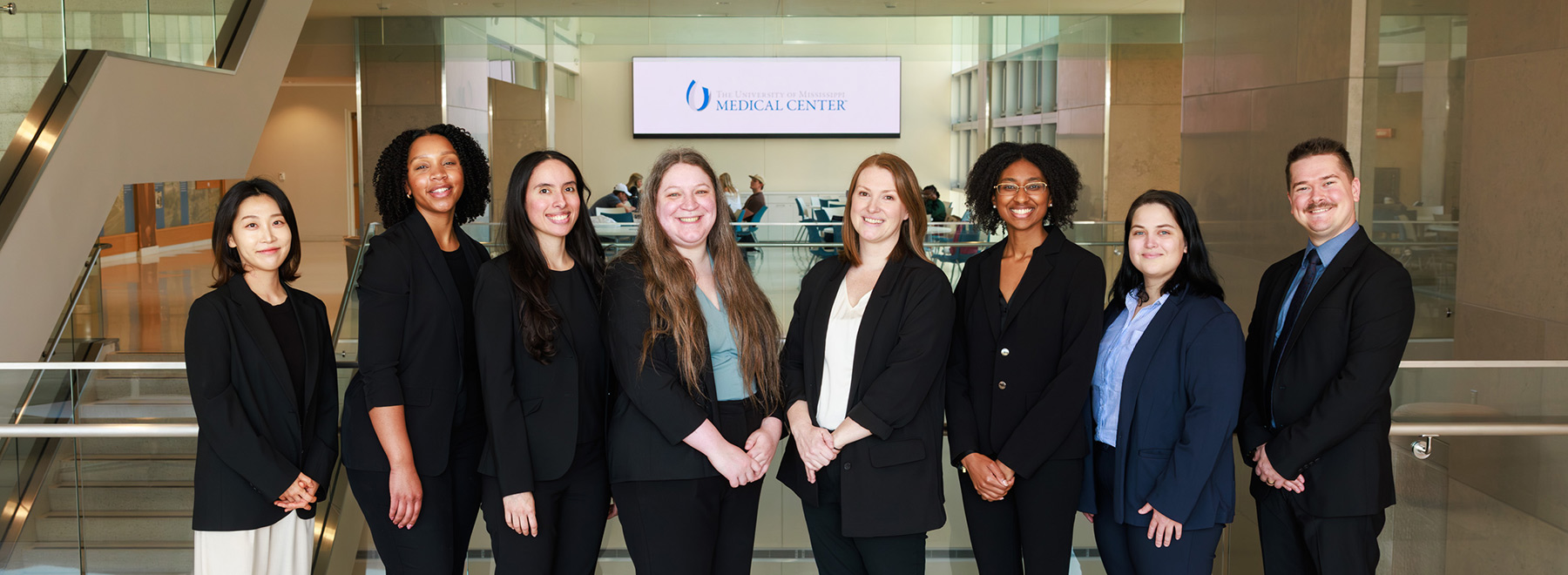 Group photo of psychology residents. A digital sign with the University of Mississippi Medical Ceter is above them in the background.